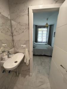 een witte badkamer met een wastafel en een slaapkamer bij The Spot Central Hostel in Sevilla