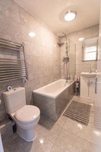 a bathroom with a toilet and a tub and a sink at Dartford Luxurious House with Parking - Netflix - Wi-Fi in Kent