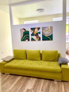 - un canapé jaune dans une pièce ornée de peintures murales dans l'établissement Dudaeva Lviv Apartments, à Lviv