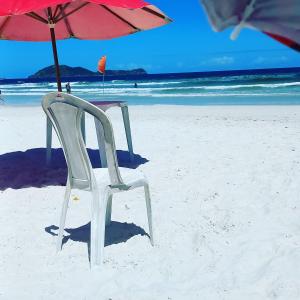 uma cadeira e um guarda-sol na praia em MANDAI Apartamento Cabo Frio em Cabo Frio