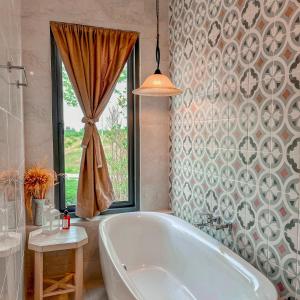 a bath tub in a bathroom with a window at Tubtao Sleepy Hill in Pong Talong