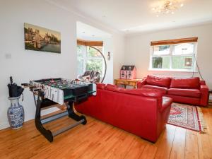 a living room with a red couch and a foosball table at Trem Y Don in Dolgarrog