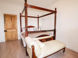 a bedroom with a four poster bed and a chair at Trem Y Don in Dolgarrog