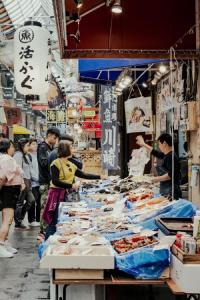 um mercado com pessoas à volta de uma mesa com comida em Folio Sakura Shinsaibashi Osaka by Banyan Group em Osaka
