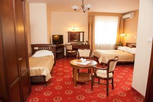 ワルシャワにあるHotel Arkadia Royalのベッド2台、テーブルと椅子が備わるホテルルームです。