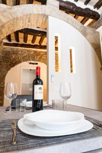 einen Tisch mit einem weißen Teller und einer Flasche Wein in der Unterkunft [Loft Rustico] in Centro Storico in Assisi