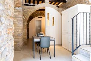 einen Tisch und Stühle in einem Zimmer mit Ziegelwand in der Unterkunft [Loft Rustico] in Centro Storico in Assisi