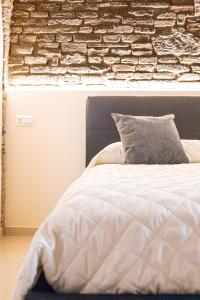 ein Schlafzimmer mit einem weißen Bett mit Ziegelwand in der Unterkunft [Loft Rustico] in Centro Storico in Assisi