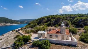 an old house on a hill next to a body of water at Phenomenal Pucisca Villa Lighthouse St Nicholas 2 Bedrooms Floor Heating & Private Jacuzzi in Pučišća