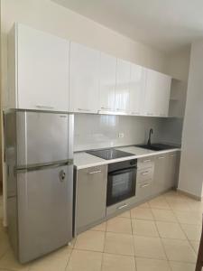 a kitchen with white cabinets and a stainless steel refrigerator at Zani’s Apartments in Durrës