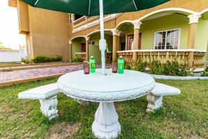 una mesa blanca con sombrilla frente a una casa en J&R Sunshine Retreat en Spanish Town