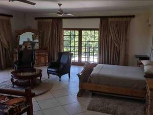 a bedroom with a bed and a chair and a mirror at The Sanctuary - Self Catering Accommodation in Mtubatuba