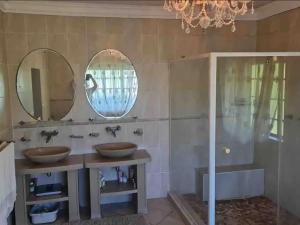 a bathroom with two sinks and two mirrors at The Sanctuary - Self Catering Accommodation in Mtubatuba