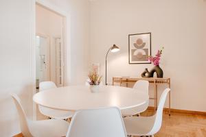 Acropolis view 4 bedroom flat في أثينا: غرفة طعام بيضاء مع طاولة بيضاء وكراسي بيضاء