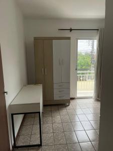 eine Küche mit einem Tisch, einem Schrank und einem Fenster in der Unterkunft APARTAMENTO PARA 4 ADULTOS EM BALNEARIO CAMBORIU in Balneário Camboriú