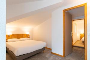 a bedroom with a bed and an open door at Hôtel Beau Site in Malbuisson