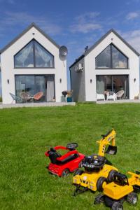 a group of toy vehicles in the grass in front of a house at Pogodne domki in Swarzewo