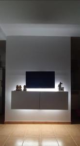 sala de estar con TV en una pared blanca en Caracola Beach, en Matalascañas