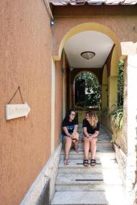 dos mujeres sentadas en las escaleras de una casa en Los Mochileros Hostel - Age Limit 18-28 en Nápoles