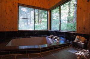 uma grande banheira num quarto com janelas em HARUNA SKY Panoramic view of Nasu,private space surrounded by fir trees,relaxing stone bath,watching movies on a 120inch big screen em Nasu