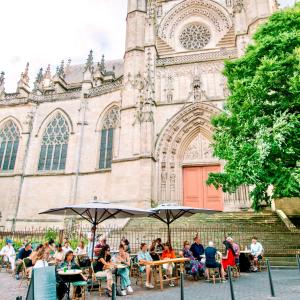 eine Gruppe von Menschen, die vor einer Kirche an Tischen sitzen in der Unterkunft LOLA Boutique Hôtel - Bordeaux Centre in Bordeaux