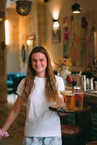 una mujer sosteniendo una bandeja de cerveza en una mesa en LOLA Boutique Hôtel - Bordeaux Centre, en Burdeos