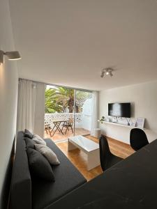 sala de estar con sofá negro y TV en Las Americas Tenerife, en Arona
