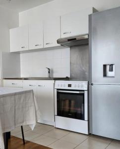 a white kitchen with a stove and a refrigerator at appartement 2 pièces 5min gare val d'Europe parking inclus in Montévrain +19 photos