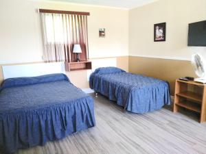 a hotel room with two beds and a flat screen tv at Motel & Camping Fort Ramsay in Gaspé