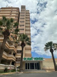 a large building with palm trees in front of it at Las Americas Tenerife in Arona