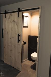 een badkamer met een houten deur naar een toilet bij Le Clos du Rempart Suite & Jacuzzi in Ciney