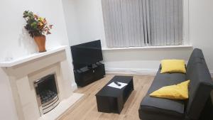 a living room with a couch and a fireplace at Arise Comfort Home - Dumers Lane, Radcliffe, Bury, Manchester in Radcliffe