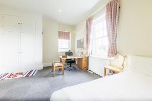 a bedroom with a bed and a desk and windows at West Dean College in West Dean