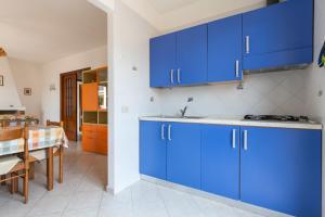 a kitchen with blue cabinets and a dining table at Vacanze Simius in Villasimius