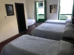a hotel room with three beds and a window at Hotel Colonial - Salamina Caldas in Salamina