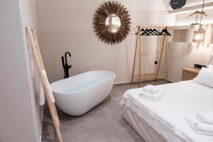 a bathroom with a bath tub next to a bed at Hayes suite syros in Ermoupoli