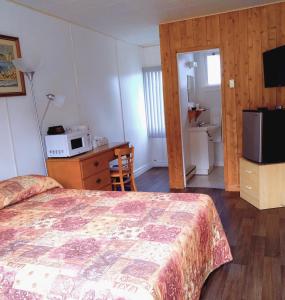 a bedroom with a bed and a desk and a microwave at Motel & Camping Fort Ramsay in Gaspé