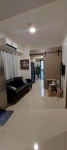 uma sala de estar com um sofá preto e uma televisão em 2 Bedroom with Balcony/ Family Room em Manila