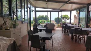 un restaurante con mesas, sillas y ventanas en Agriturismo La Focazza, en Ascea