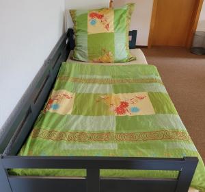 ein Bett mit einer grünen Decke und Kissen darauf in der Unterkunft Ferienwohnung im Schwarzwaldhaus in Behla