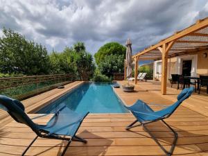 a deck with two chairs and a swimming pool at Villa spacieuse Piscine, terrain de petanque in Villeveyrac