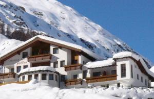 a snow covered building in front of a mountain at Soliva Hotel & Apartments by MEIN SAMNAUN - MOUNTAIN HOMES in Samnaun
