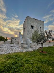 a stone building with stairs and a tree in a field at Achelatis Traditional Guest Houses in Areopolis