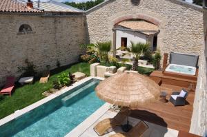 un patio con sombrilla y piscina en Le Mas de Fanfan, en Le Cailar