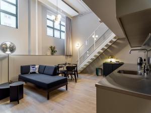 斯德哥尔摩Unity Hammarby Sjöstad - A Studio Hotel的带沙发、水槽和楼梯的客厅