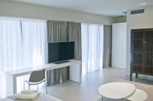 Una sala de estar con un televisor y una mesa y sillas. en Serennia Exclusive Rooms, en Barcelona
