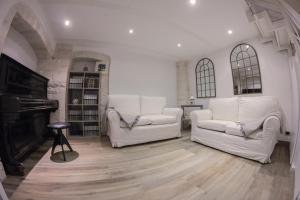 un soggiorno con due sedie bianche e un pianoforte di Le Dimore del Casalvecchio a Conversano