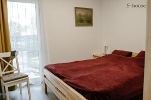 ein Schlafzimmer mit einem Bett, einem Stuhl und einem Fenster in der Unterkunft Vacation house in Saulkrasti