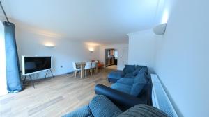 sala de estar con sofá azul y TV en Large 6 bed house - 6 Bedrooms - Parking WIFI 6 smart TVs 3 shower rooms 4 WCs, en Kettering