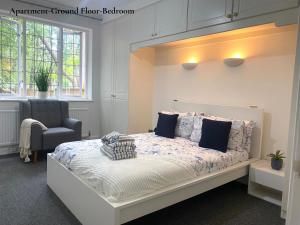 - une chambre avec un grand lit et une chaise dans l'établissement Cosy Apartments Near Hampstead Heath With Free On-Site Parking & Private Gardens, Golders Green, à Londres